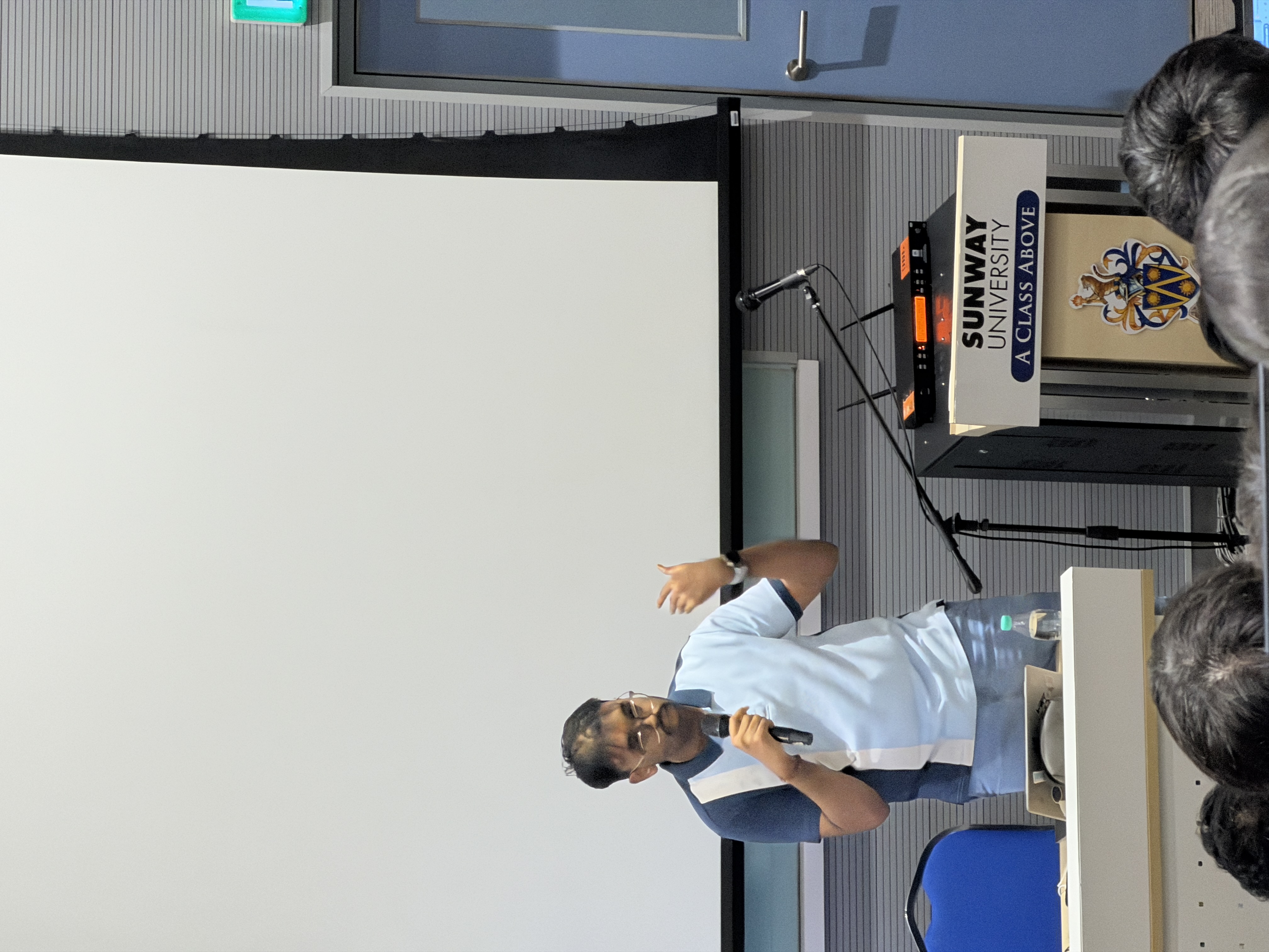 Puvaan Raaj holding a microphone and gesturing while presenting at Sunway University